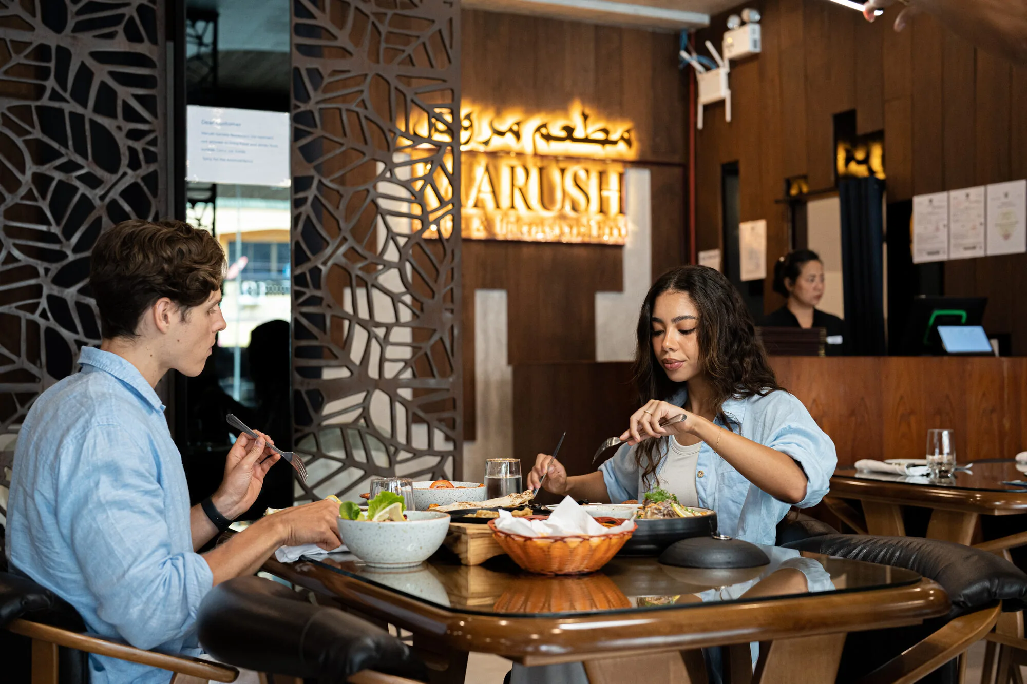 Couple enjoying a meal at Marush Kamala under the illuminated sign.